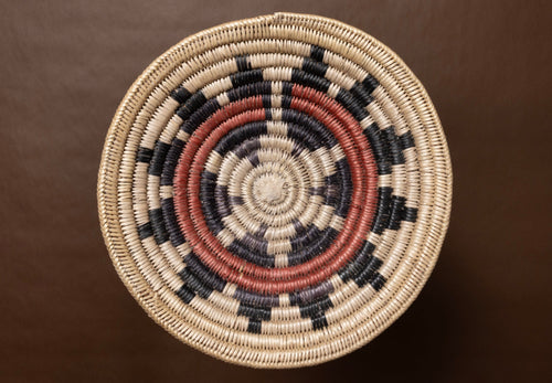 Vintage hand-woven basket with concentric circle pattern on a brown background
