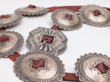 Brown leather belt with silver concho-style buckles on a white background