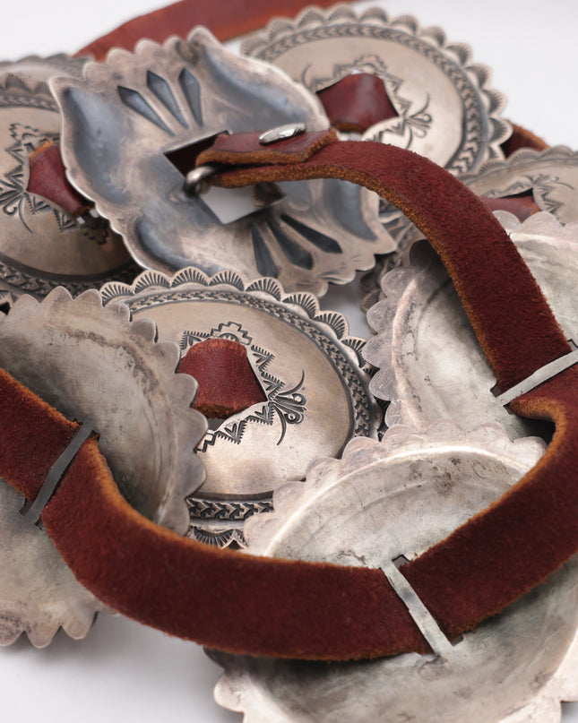 Silver concho belt with brown leather on a white background