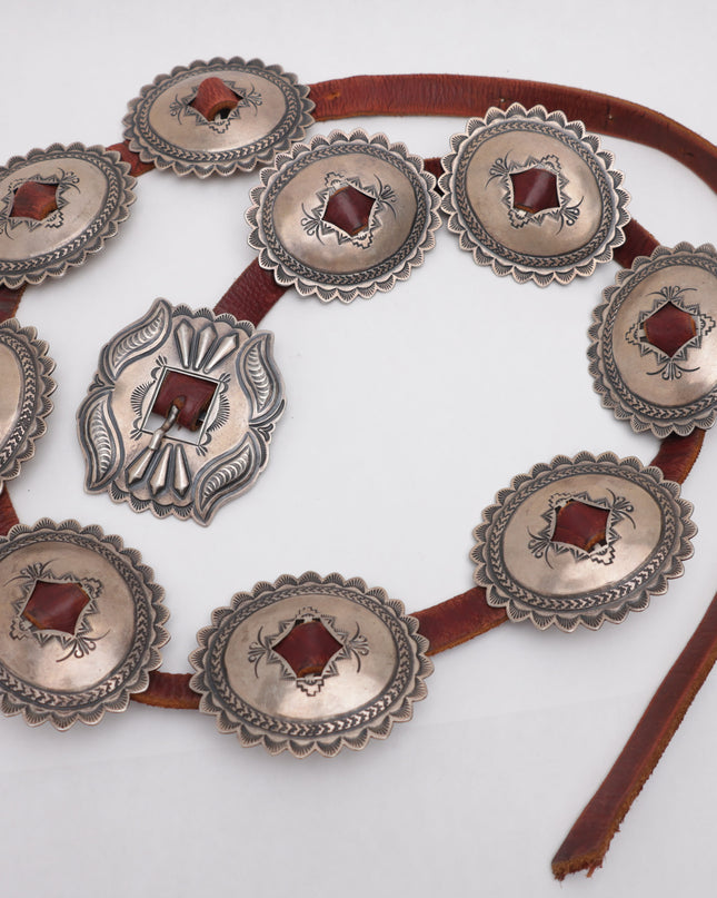 Navajo Concho belt with 9 silver concho plates on brown leather on a white background