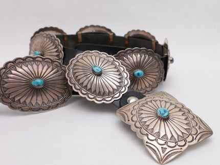 Black leather concho belt with silver concho buckles on a white background