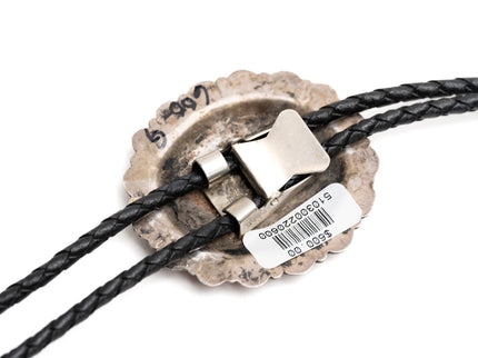 Close-up of the back of a silver bolo tie with a metal clasp and black braided cord on a white background