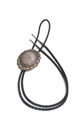 Vintage Navajo Silver Stamped Bolo-Tie with black braided leather cords on a white background