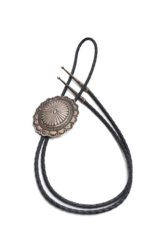 Vintage Navajo Silver Stamped Bolo-Tie with black braided leather cords on a white background