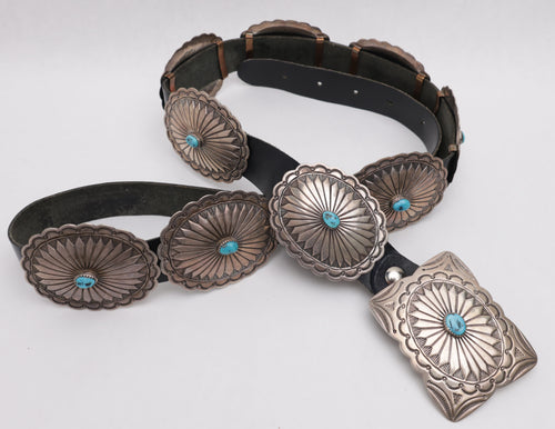 Black leather concho belt with silver concho buckles on a white background