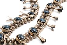 Load image into Gallery viewer, A close-up image of a vintage squash blossom necklace with lapis stones and metal accents, displaying the detailed craftsmanship and the vibrant blue color of the lapis.
