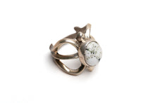 Load image into Gallery viewer, Top view of silver cast cut-out ring showcases a single, centrally set round white buffalo stone on a white background. Ring appears gold because of the natural patina
