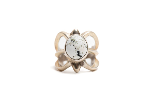 Silver cast cut-out ring showcases a single, centrally set round white buffalo stone. Ring appears gold because of the natural patina