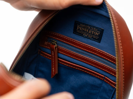 Close-up of a Pendleton leather bag with open zipper showing blue interior.