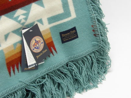 Pendleton Chief Joseph shawl in aqua, featuring a traditional Native American-inspired geometric pattern with arrow motifs, folded neatly to show intricate design and soft wool texture, Tag View