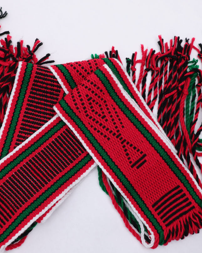 Dark red traditional sash with two green lines and black and white highlights rolled up on a white background