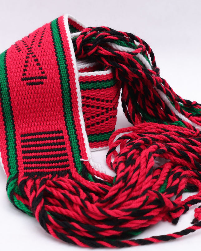 Dark red traditional sash with two green lines and black and white highlights rolled up on a white background