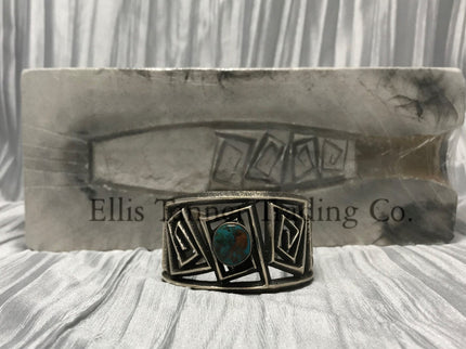 A silver Cuff with a rough silver square maze cutout. In the center is a round Royston Turquoise stone.