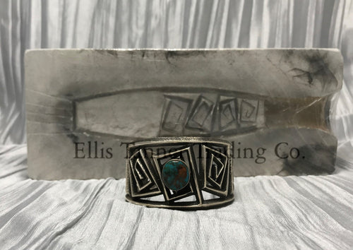 A silver Cuff with a rough silver square maze cutout. In the center is a round Royston Turquoise stone.