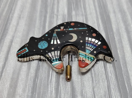 A silver pin with an inlayed bear design featuring various stones such as onyx, mother of pearl, coral, pink shell, and abalone lapis.
