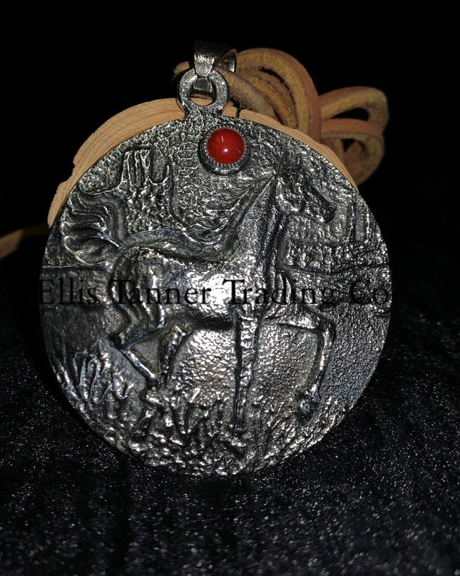A circle silver pendant with a sand cast horse and one coral stone, with a tan leather strap. Displayed on top of a black cloth  front