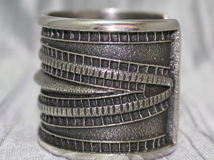 Large Sand Cast Cuff. Crafted from sterling silver using the sand cast technique, this cuff features unique texture and shine, on a shiny silver cloth.