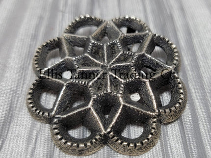 Silver Cut out sand cast, pendant displayed on top of a shiny silver cloth 