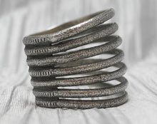 Load image into Gallery viewer, A multi-band silver cuff bracelet with a textured, rustic finish, featuring evenly spaced horizontal bands stacked in an open design. The bracelet is showcased against a soft, neutral background, emphasizing its unique craftsmanship and versatile style.
