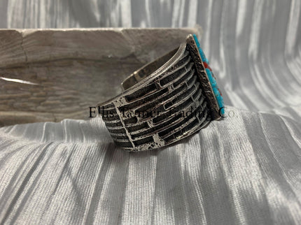 Displayed is a silver tufa cobbletone bracelet, on a silver shiny sheet side view