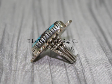 Side profile of a Bisbee Turquoise ring showcasing the raised oval turquoise stone with brown veining, set in a detailed silver bezel. the band’s craftsmanship is visible, emphasizing the ring's dimensional design.