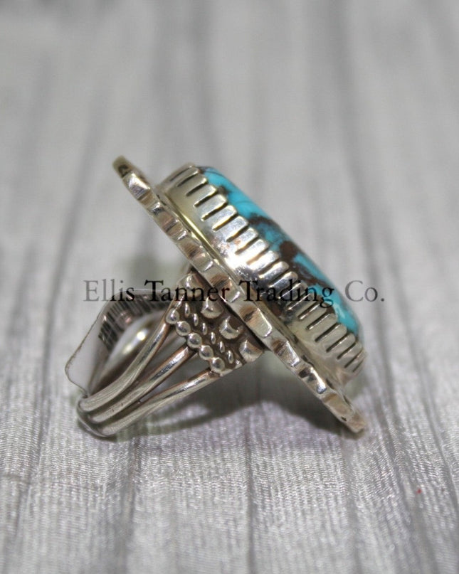 Side profile of a Bisbee Turquoise ring showcasing the raised oval turquoise stone with brown veining, set in a detailed silver bezel. the band’s craftsmanship is visible, emphasizing the ring's dimensional design.