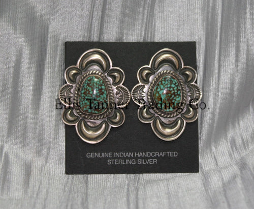 Silver stamped clip on earrings, with a center #8 Turquoise surrounded by a silver rope. displayed on a black card on top of a silver sheet 