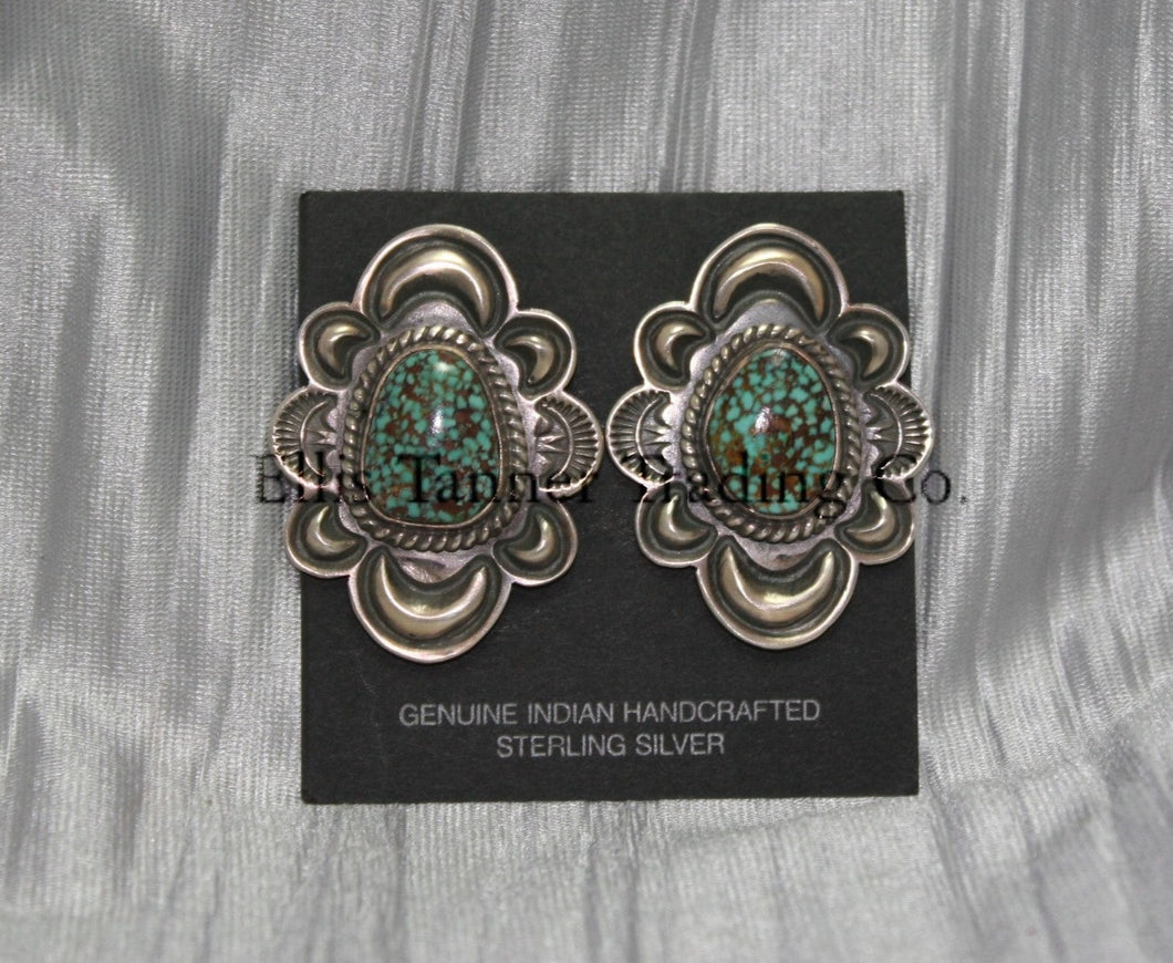 Silver stamped clip on earrings, with a center #8 Turquoise surrounded by a silver rope. displayed on a black card on top of a silver sheet 