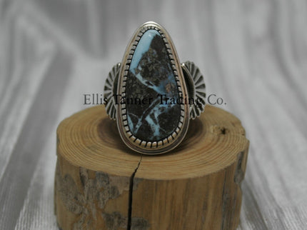 Tommy Jackson Black Diamond Turquoise Teardrop Stone silver overlay sides on top of a wooden display Front View 