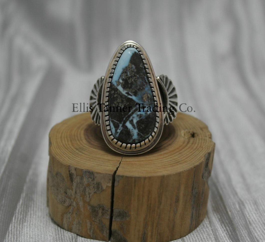 Tommy Jackson Black Diamond Turquoise Teardrop Stone silver overlay sides on top of a wooden display Front View 