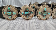 Load image into Gallery viewer, A handcrafted Navajo concho belt with detailed sterling silver conchos, each embedded with mixed turquoise stones of varying shades and natural patterns, attached to a black leather strap.
