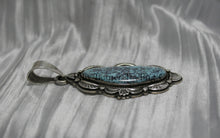 Load image into Gallery viewer, A handcrafted sterling silver pendant with a Morenci Turquoise gemstone. The stone is blue with a black and gray matrix and is set in an ornate silver frame with scalloped and stamped detailing. The pendant features a large bail for easy attachment to a chain.
