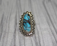 Load image into Gallery viewer, An oval-shaped Bisbee Turquoise with black vein matrix. surrounded in a silver starburst border. this ring is displayed on top of a gray cloth 

