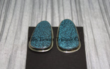 Load image into Gallery viewer, slab-style clip-on earrings featuring polished #8 turquoise stones with a speckled pattern, set in sterling silver bezels, displayed on a black card against a textured silver background. 
